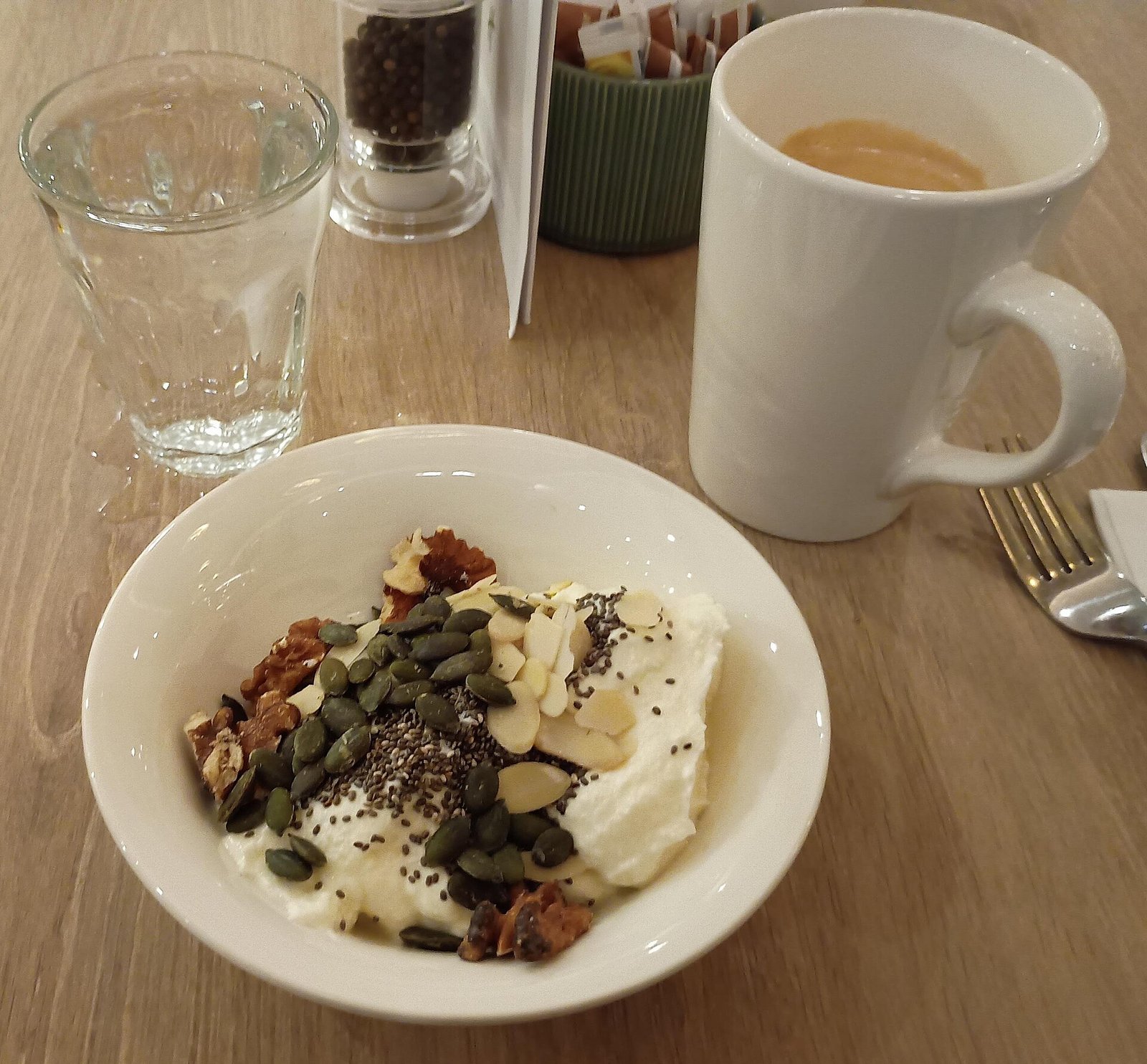 Bowl of Greek yogurt topped with walnuts and seeds