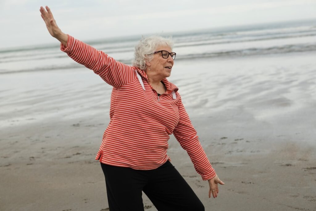 Older woman practicing tai chi on the beach for balance training