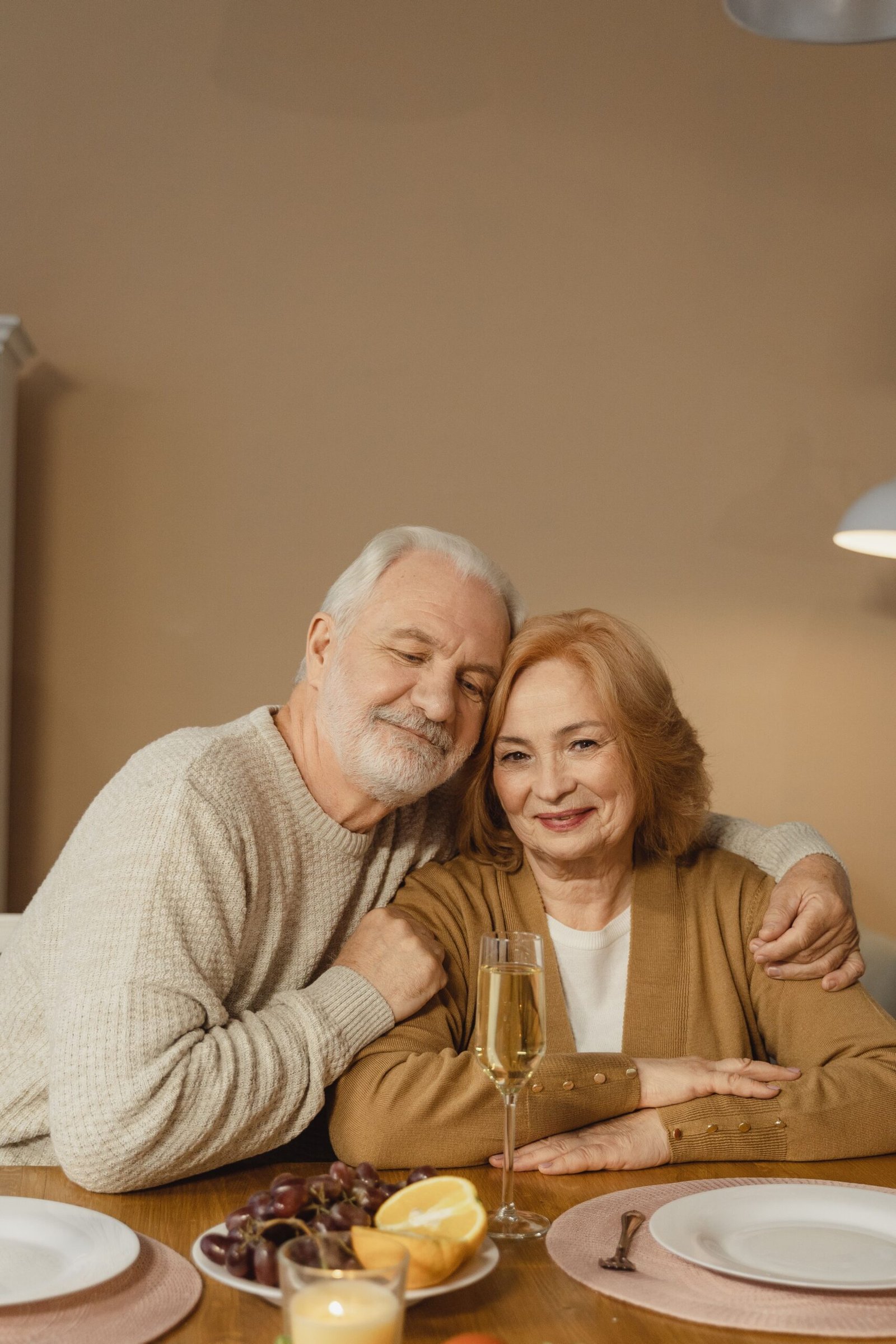 Elderly couple sharing a warm moment over a home-cooked dinner table