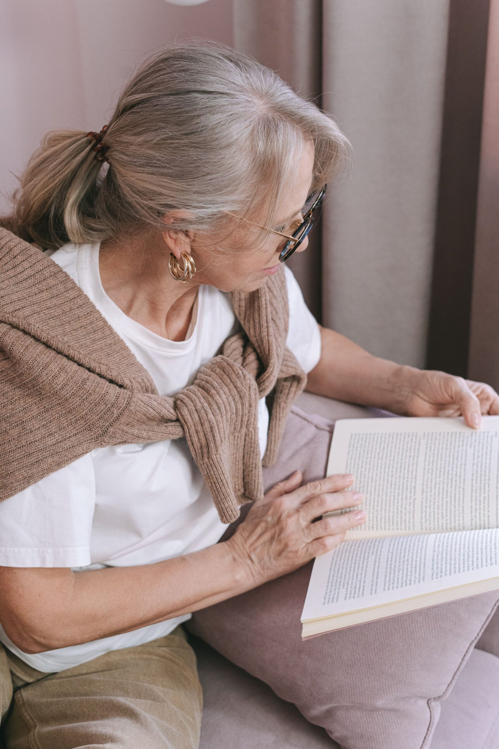 Older woman reading a book comfortably at home