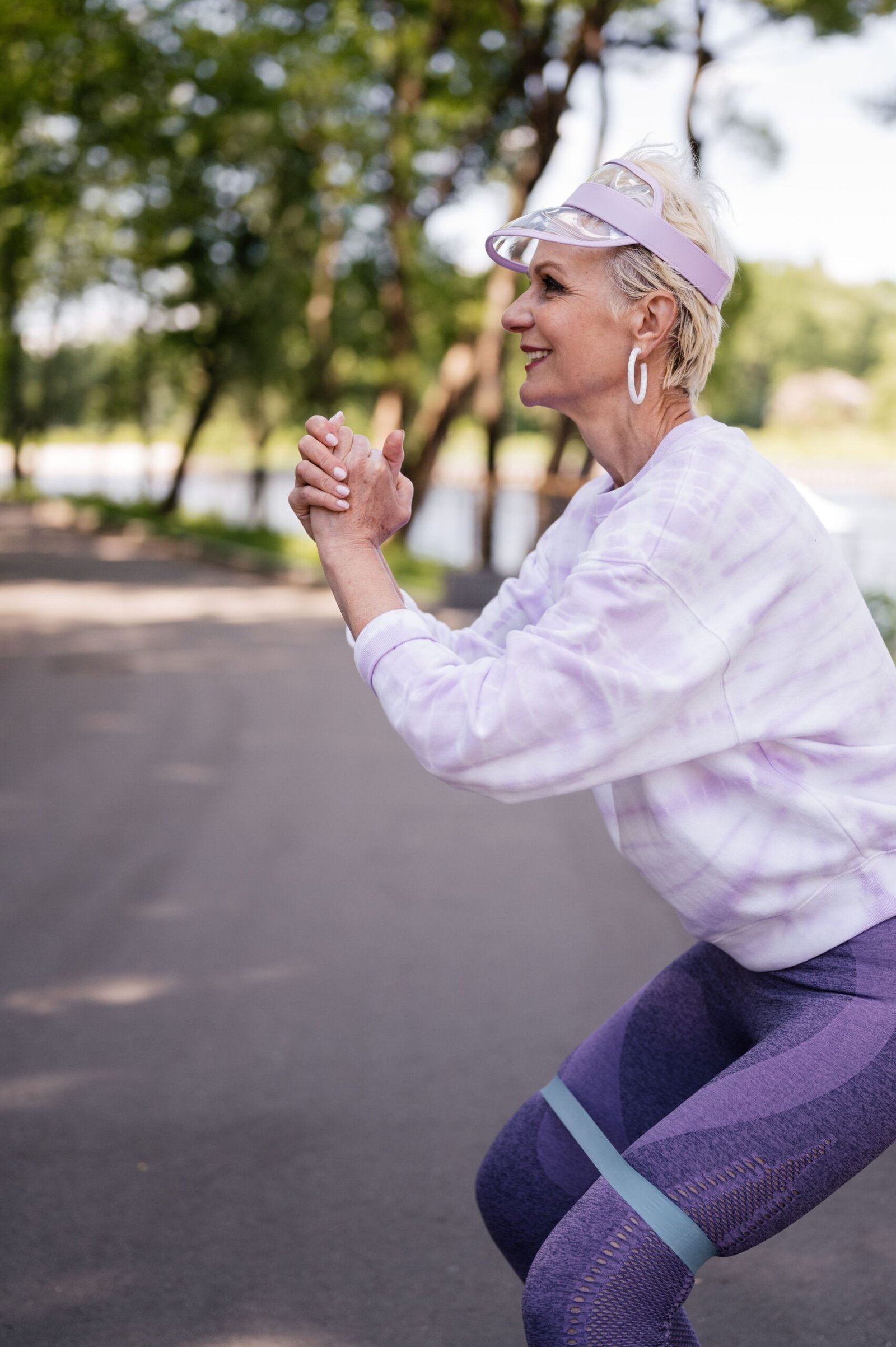 Senior woman performing a resistance band exercise outdoors in a park