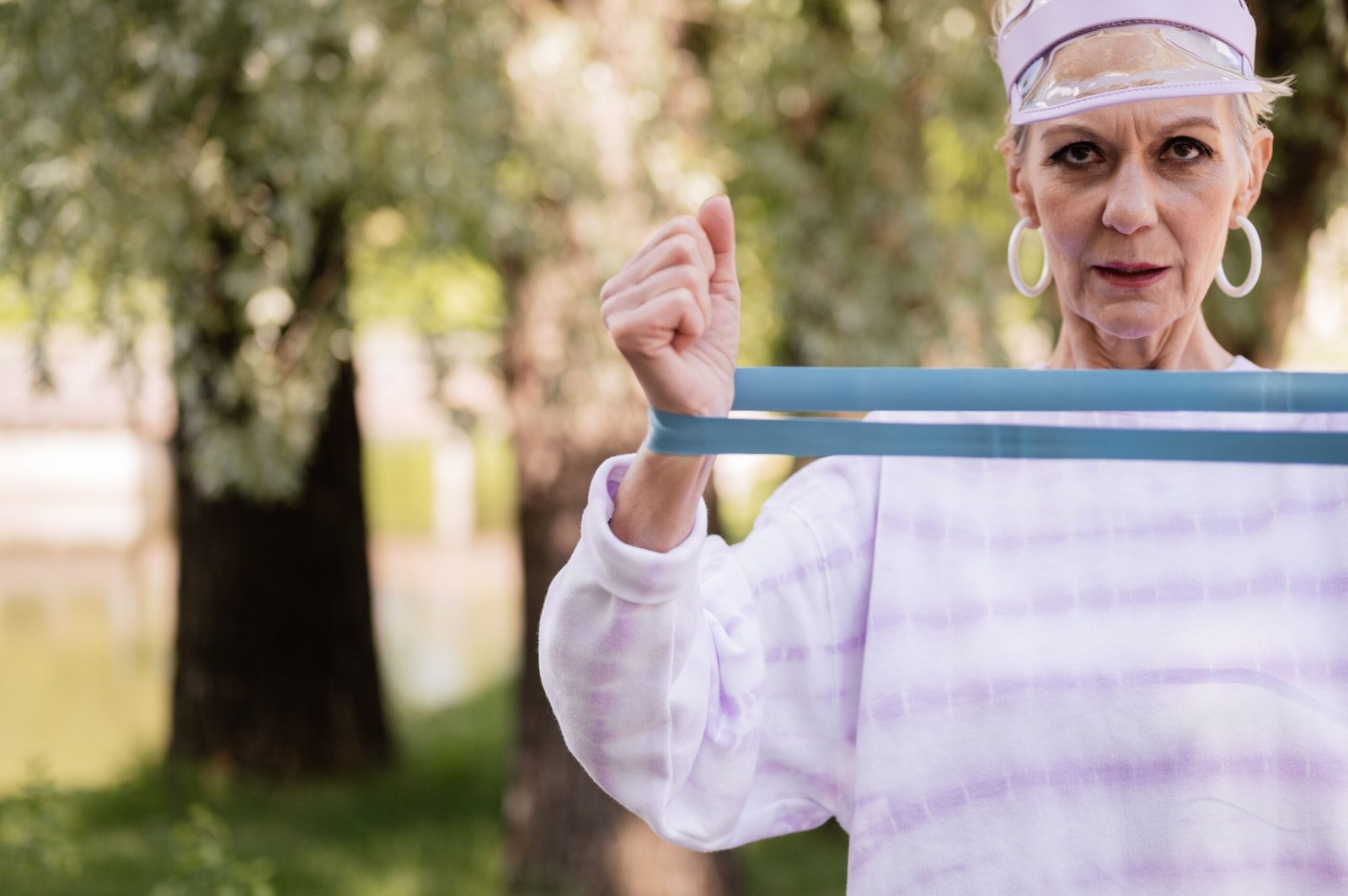 Senior woman working out with a resistance band in a park, close up