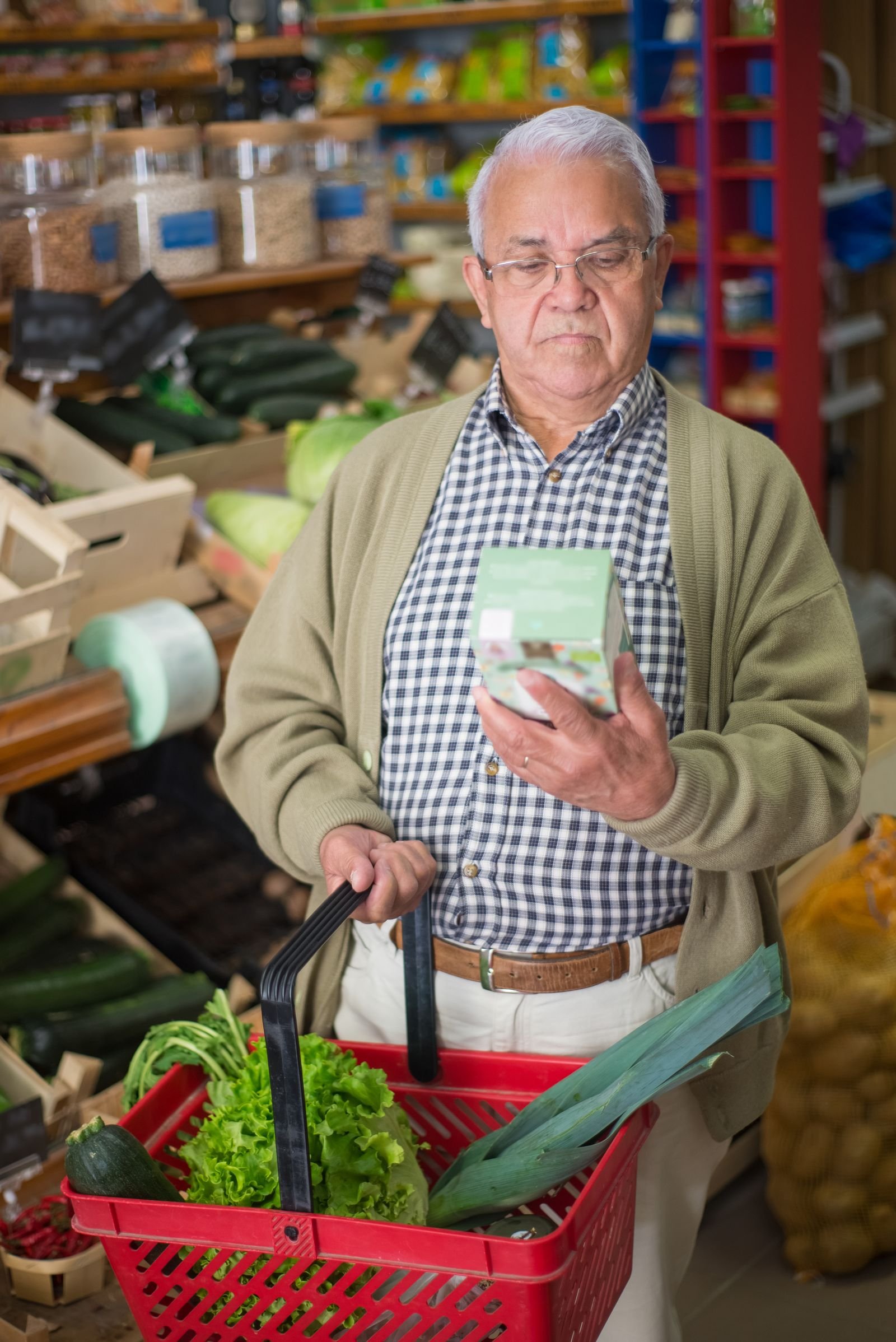 Elderly man examining a product while grocery shopping