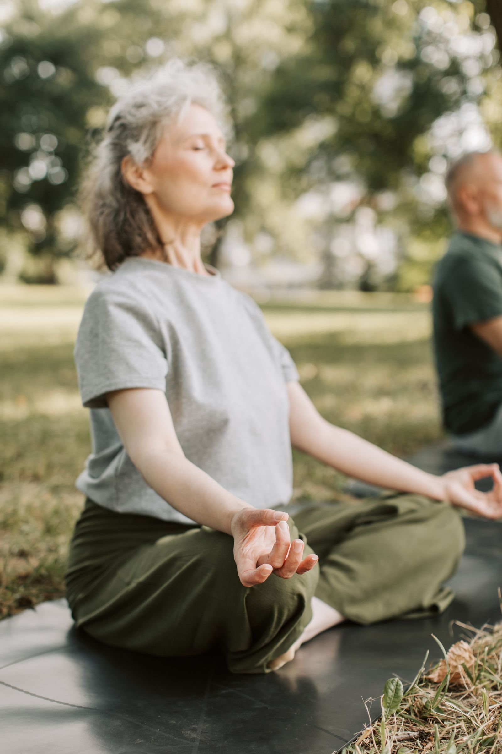 Elderly woman meditating peacefully outdoors with eyes closed