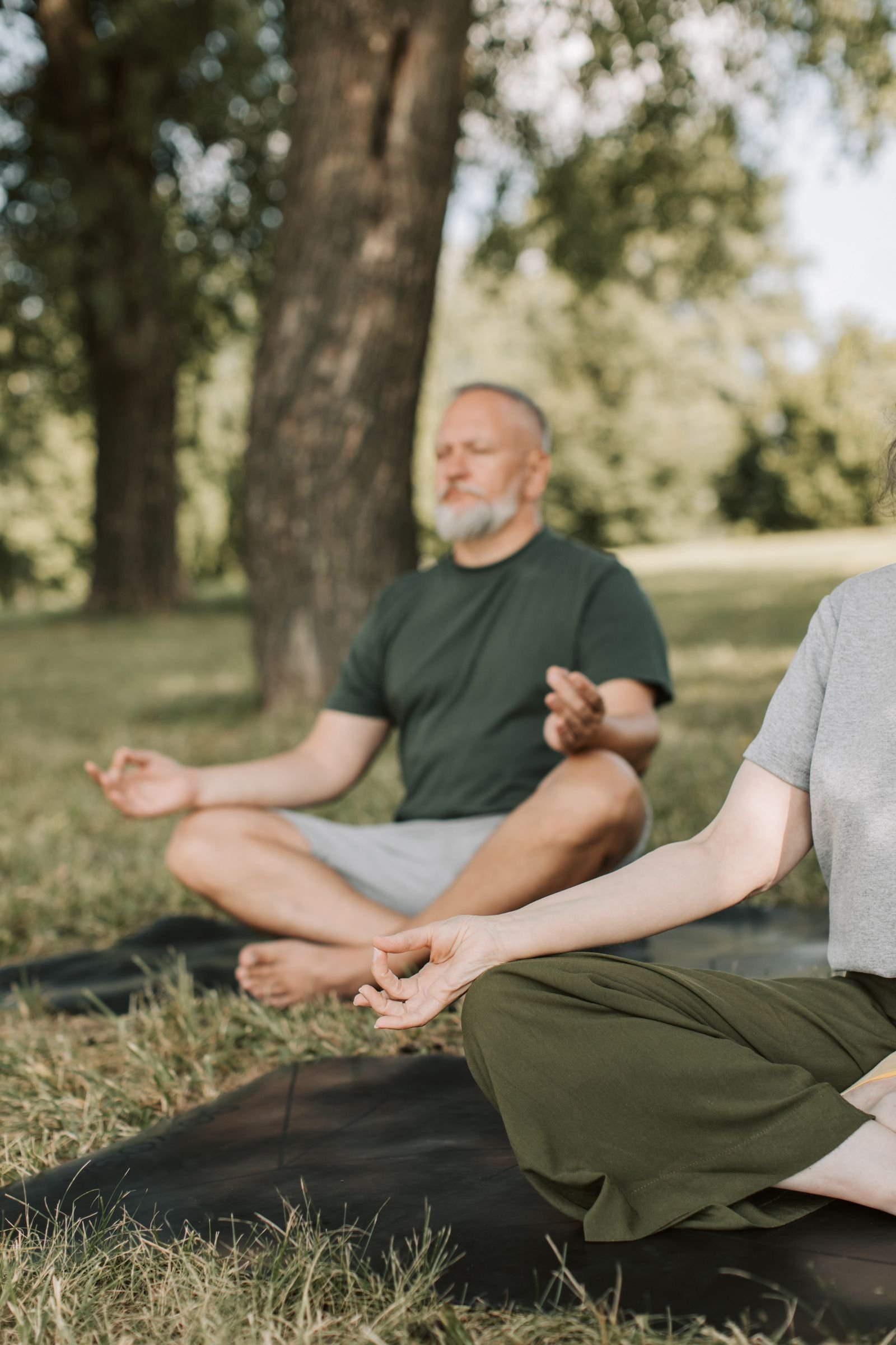 Elderly man meditating outdoors as part of a stress-relief practice