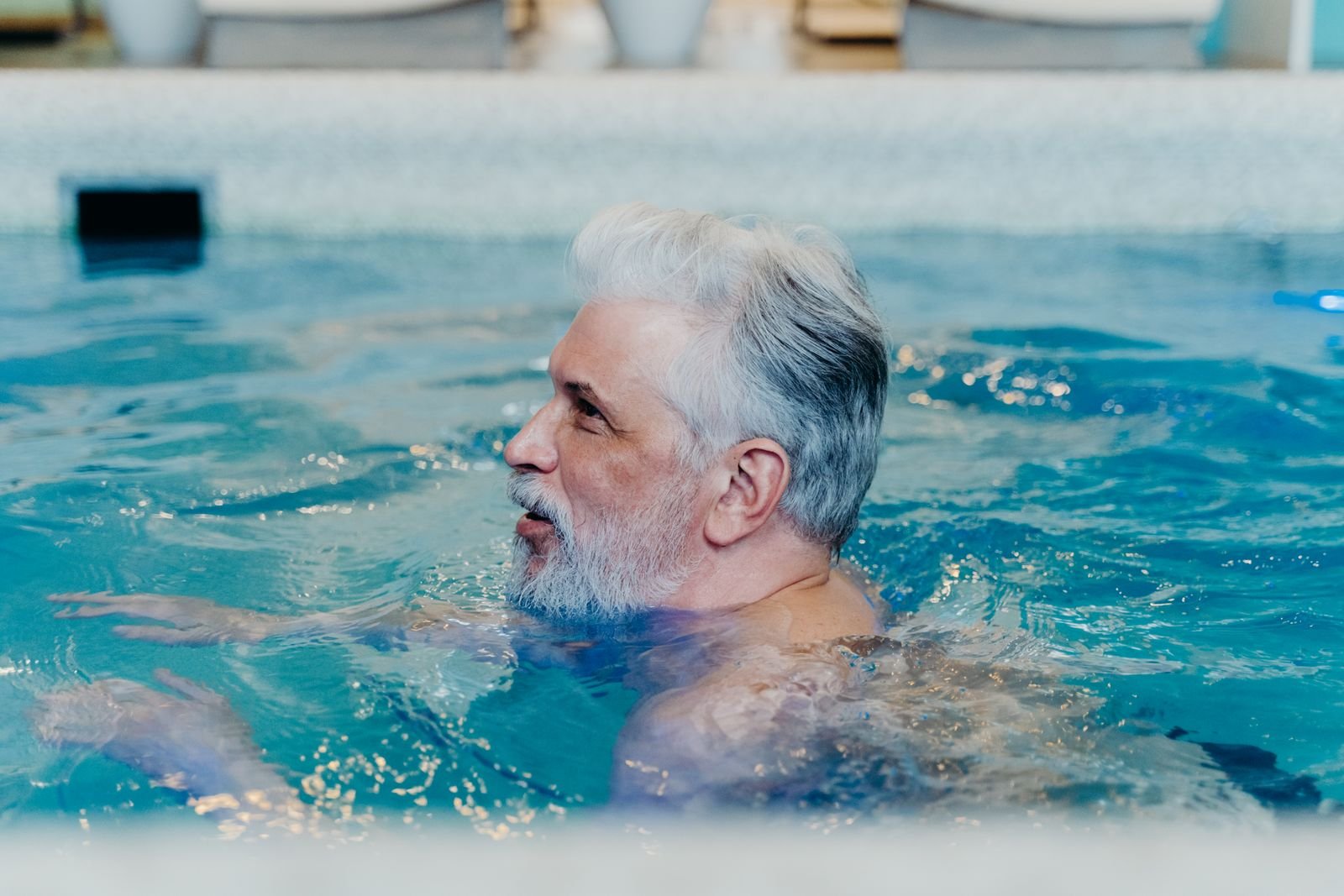 Senior man with grey hair swimming laps in a pool