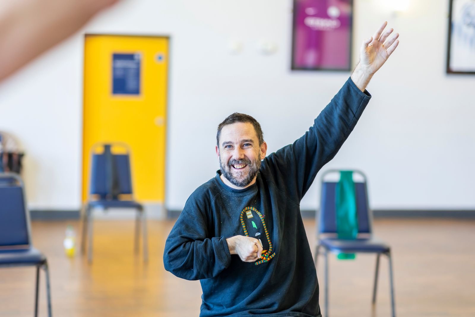 Older man smiling while raising his arm during an indoor exercise session