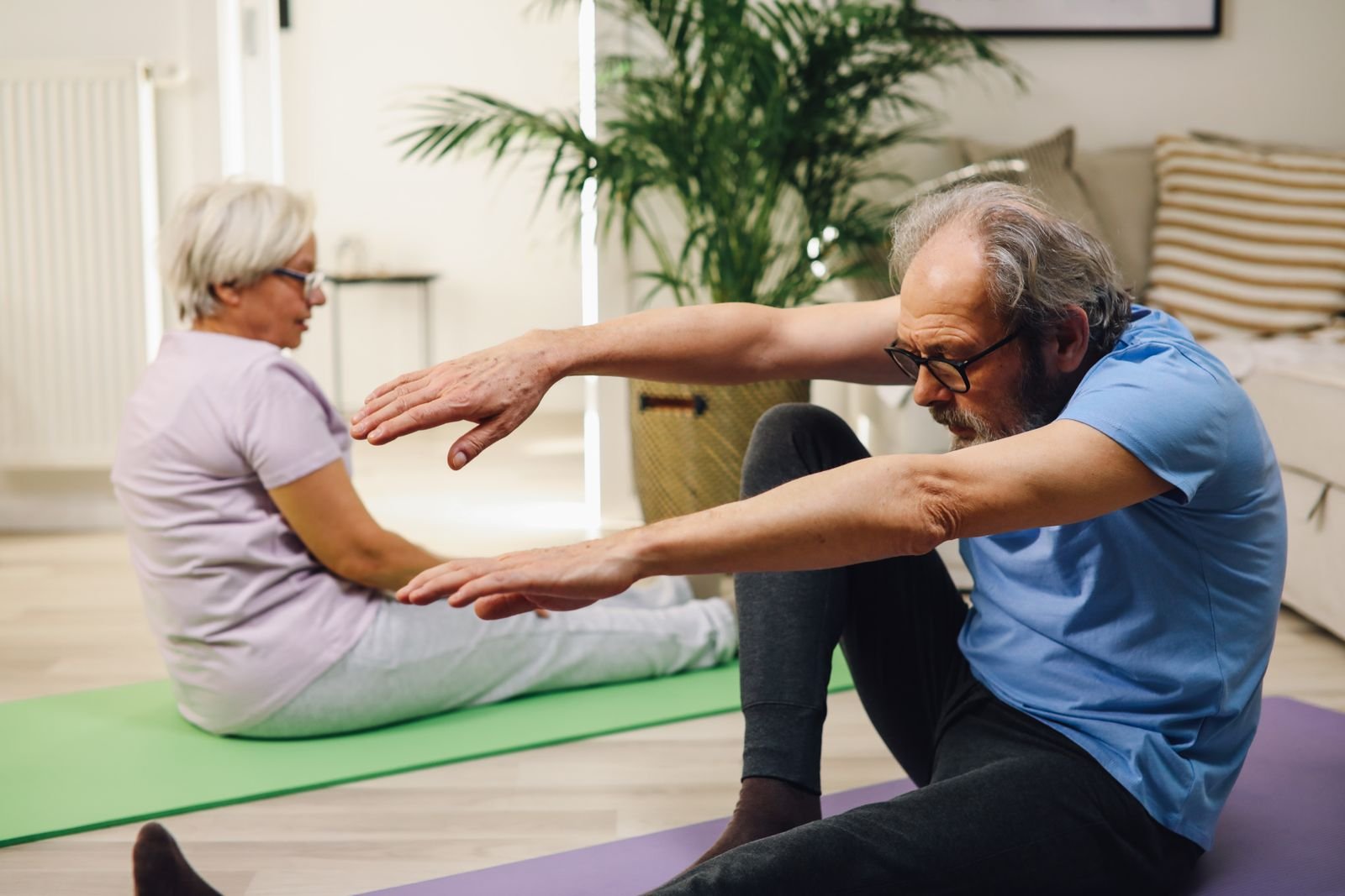 Older couple doing floor exercises together at home to build strength