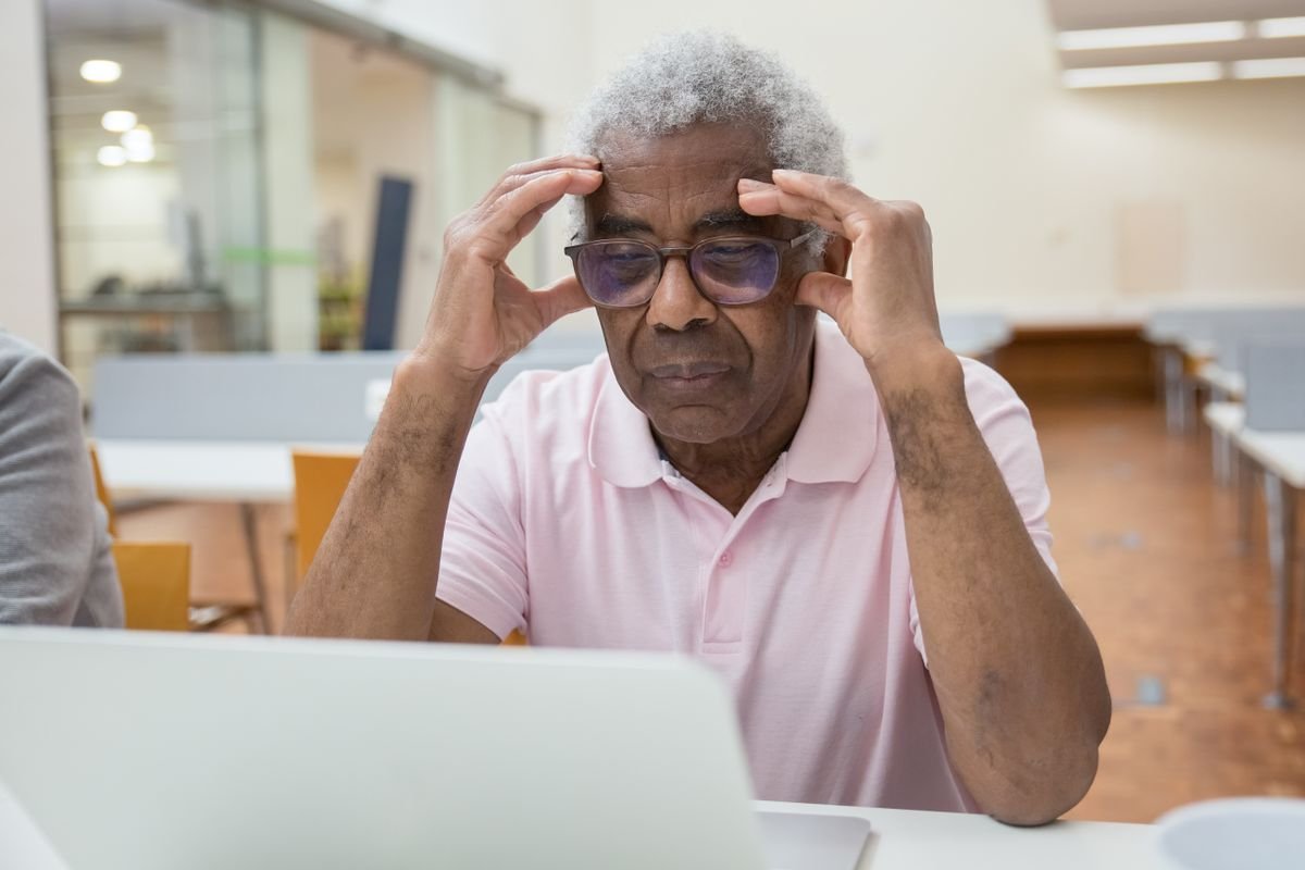 Older Black man engaged and learning on a laptop at home
