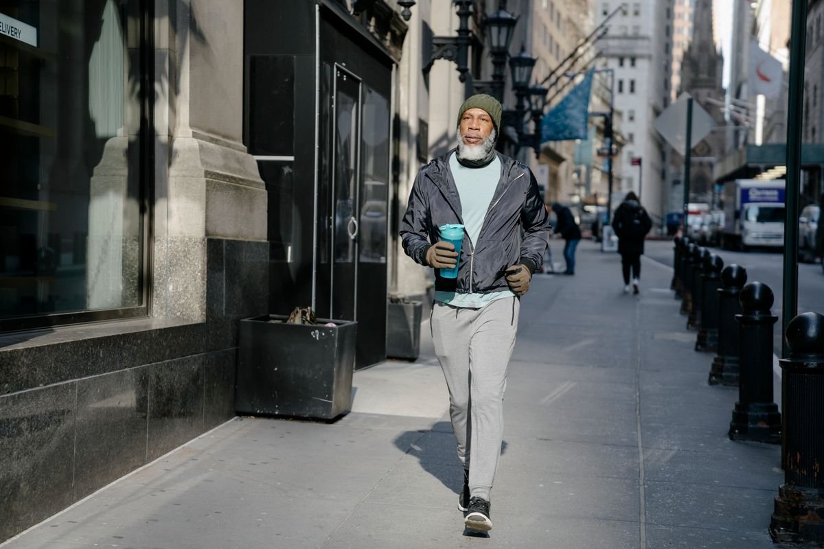 Senior Black man walking briskly on a city sidewalk, staying active