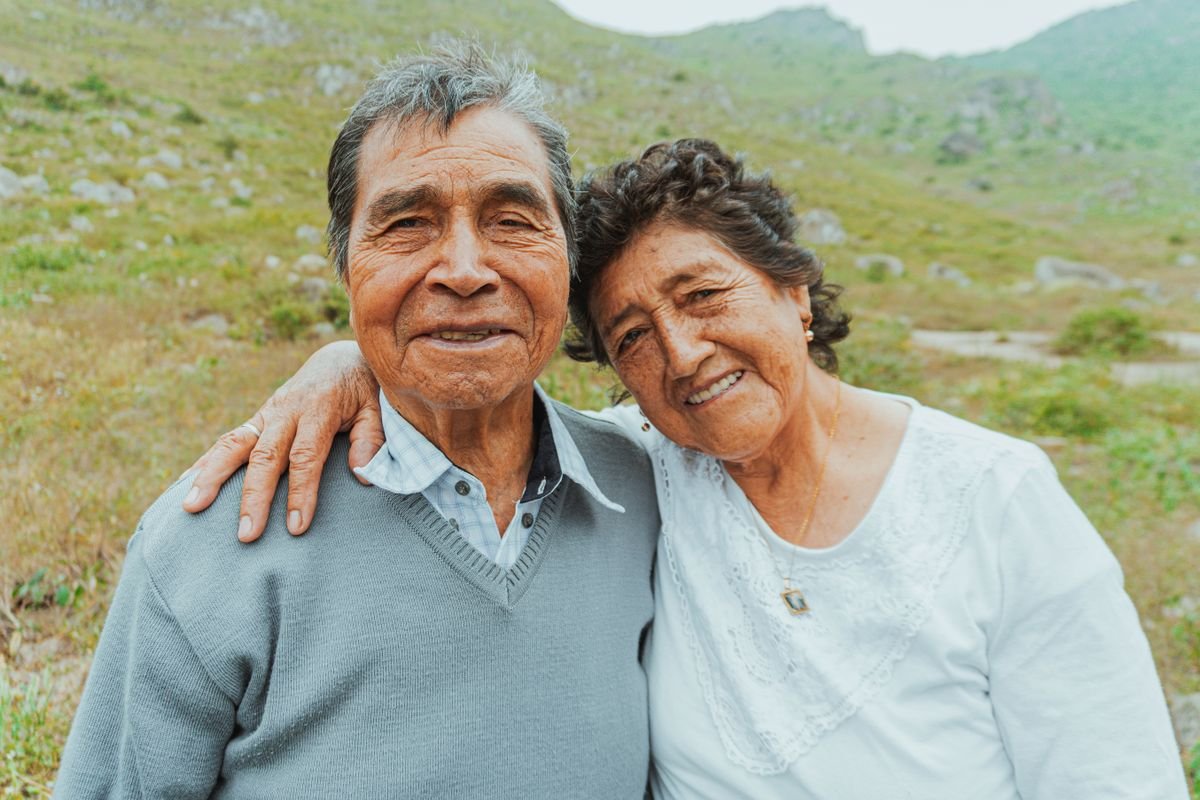 Smiling elderly Latino couple embracing outdoors in a scenic mountain setting
