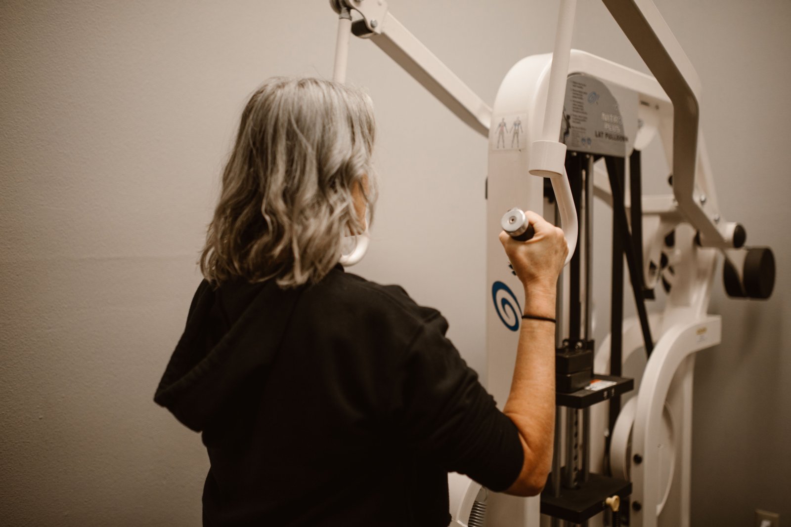 Senior woman using a lat pulldown machine in the gym for strength training.