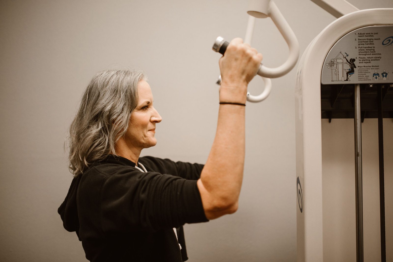 Active senior woman working out on gym equipment, focusing on strength and wellness.