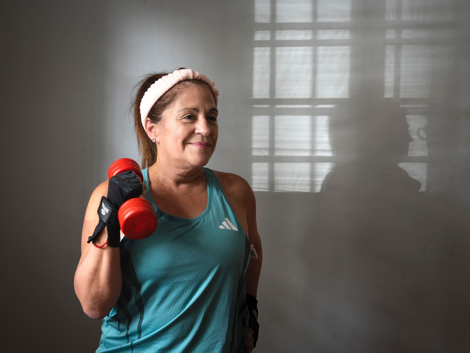 Latina senior woman exercising with dumbbells indoors, showcasing strength training