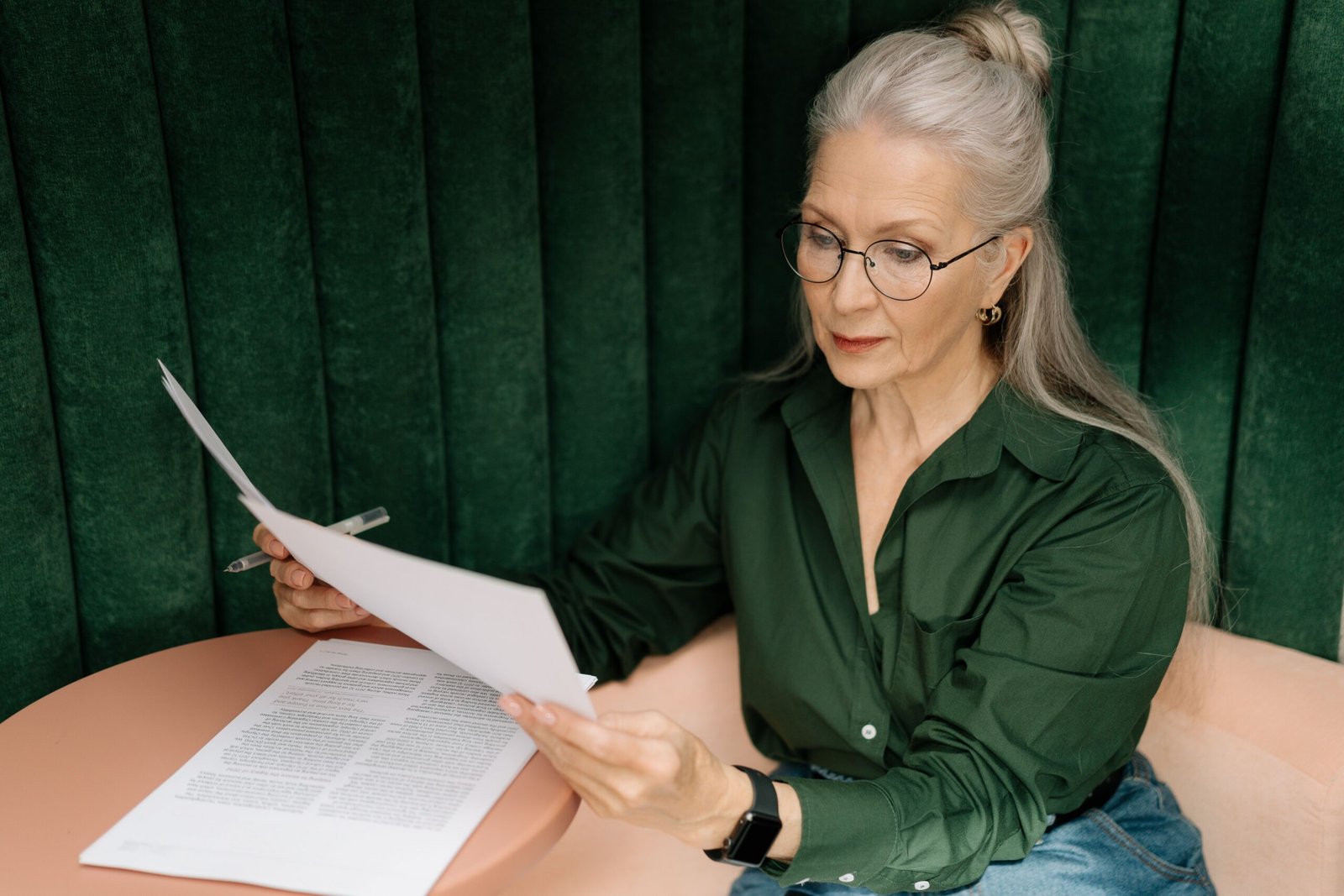 Older woman wearing eyeglasses reading at a table indoors
