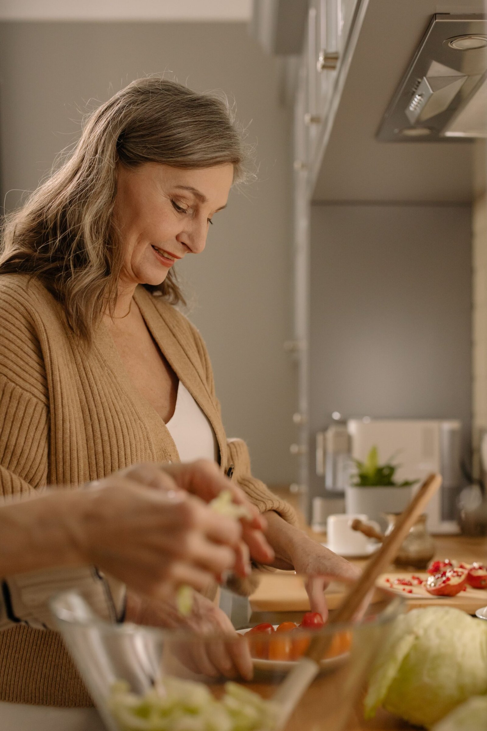 Woman in her sixties smiling while preparing a healthy meal in the kitchen
