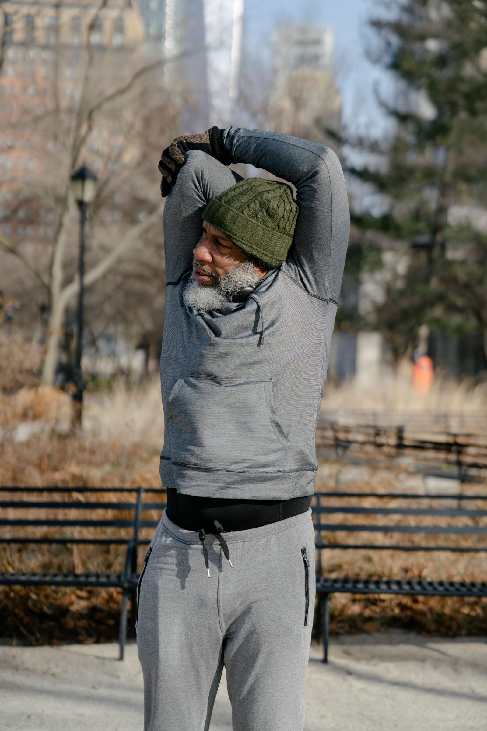 Senior Black man stretching his arms outdoors in a park, warming up before exercise