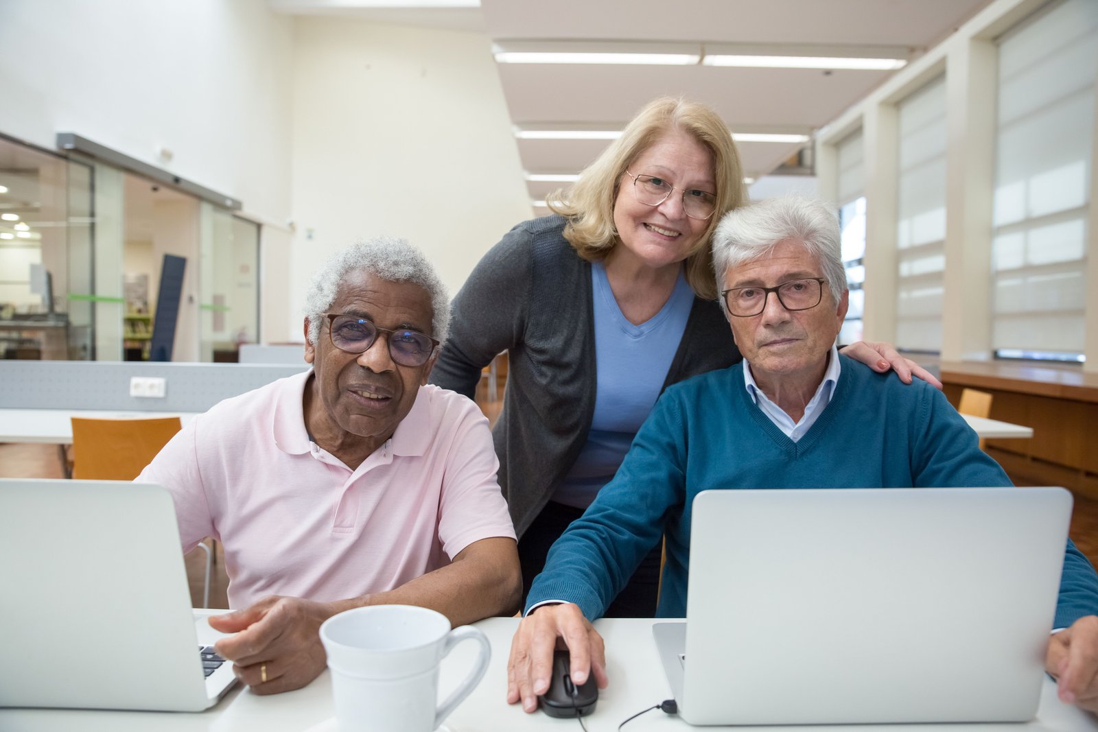 Elderly adults engaged and enjoying a computer class together indoors