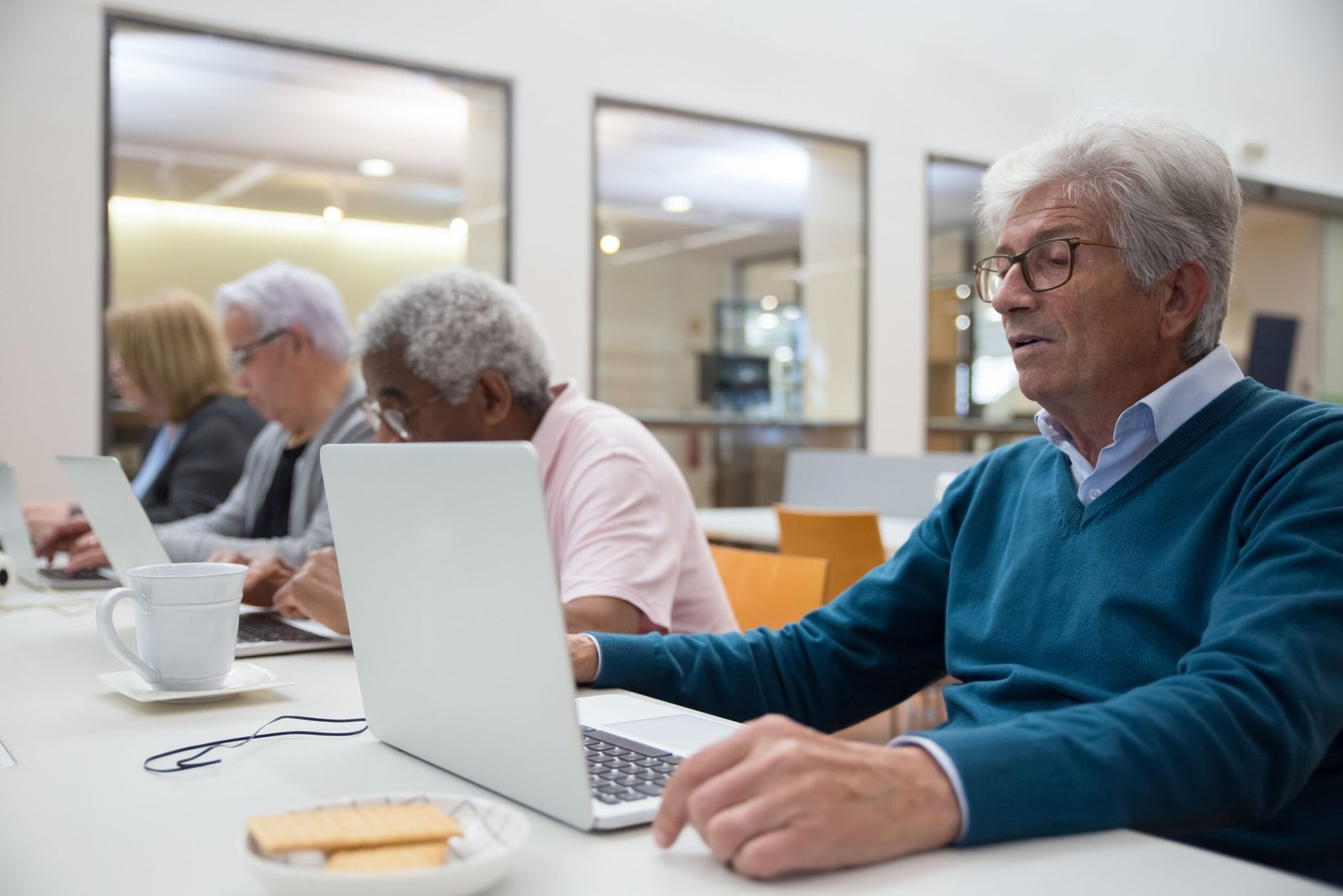 Seniors learning computer skills together in a classroom setting
