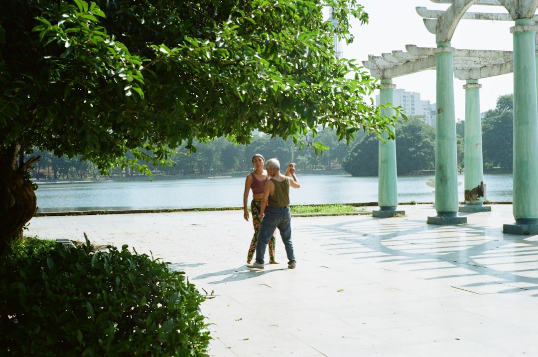 Two older men practicing tai chi together by a lake