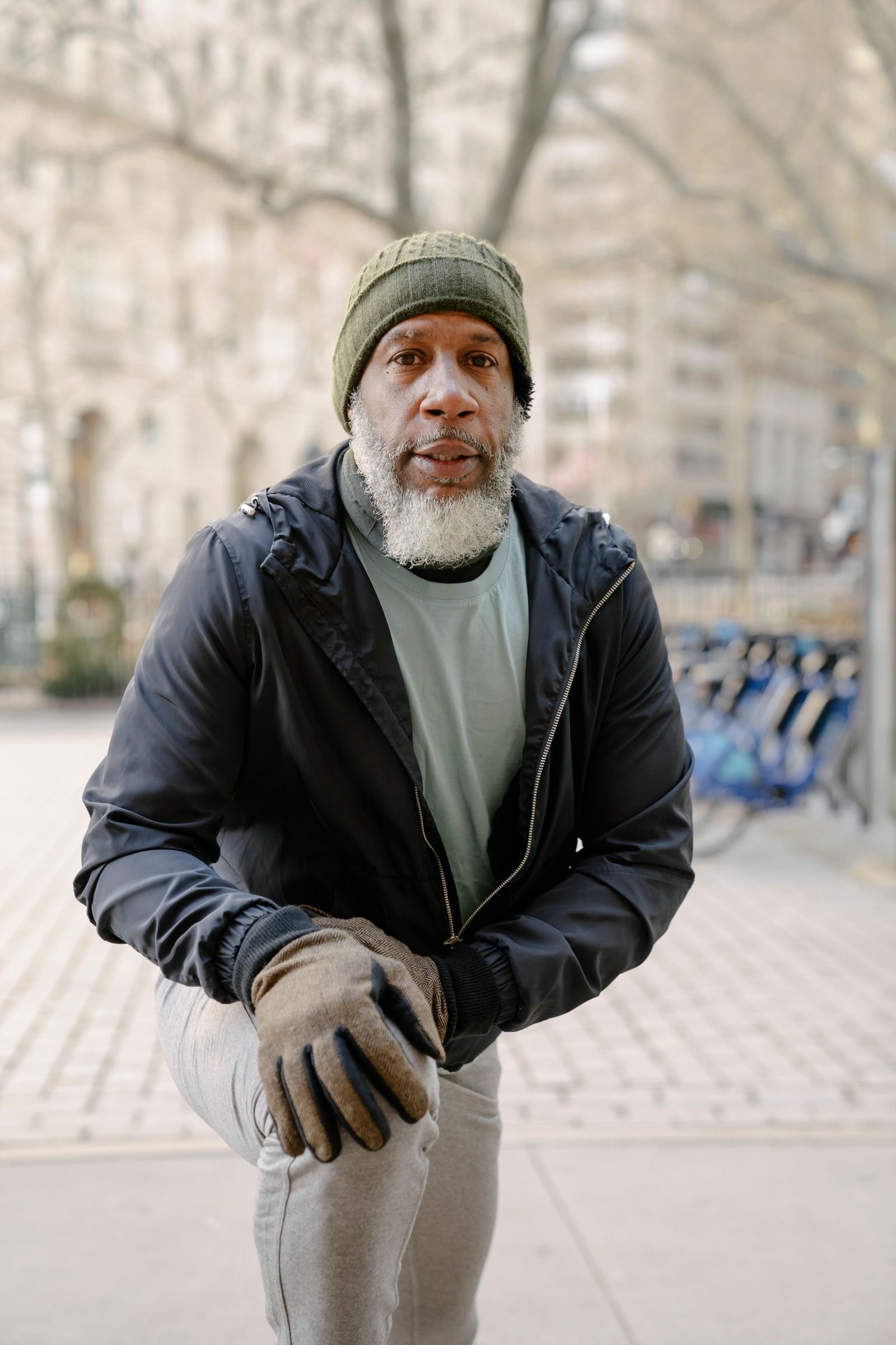 Senior bearded Black man stretching his legs outdoors in a park.