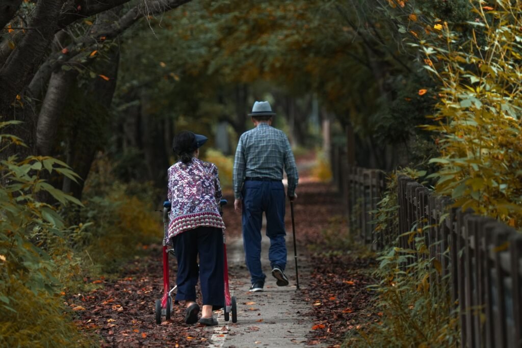 Older Asian couple walking together along an autumn forest path