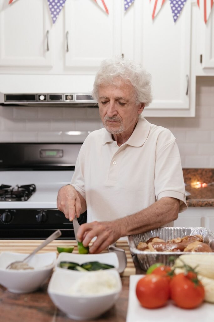 Older man chopping fresh vegetables at his kitchen counter