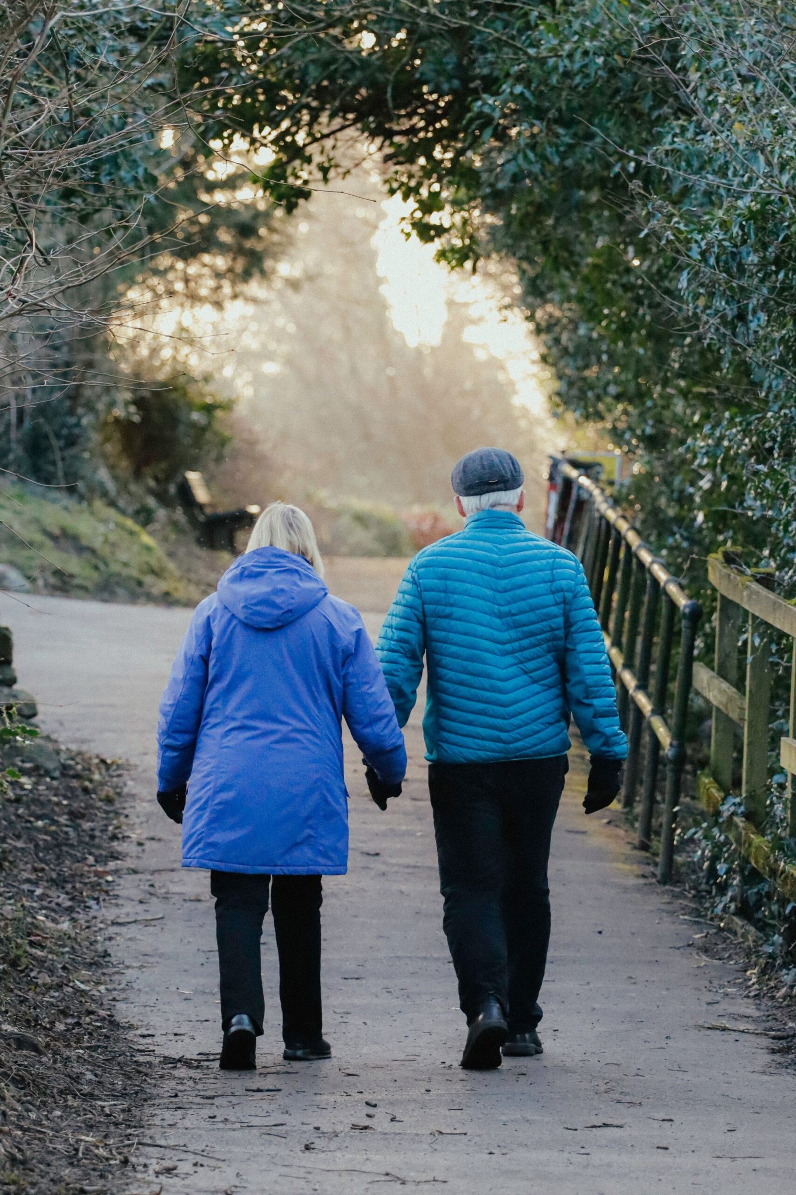 A senior couple walking together on a park path at sunset