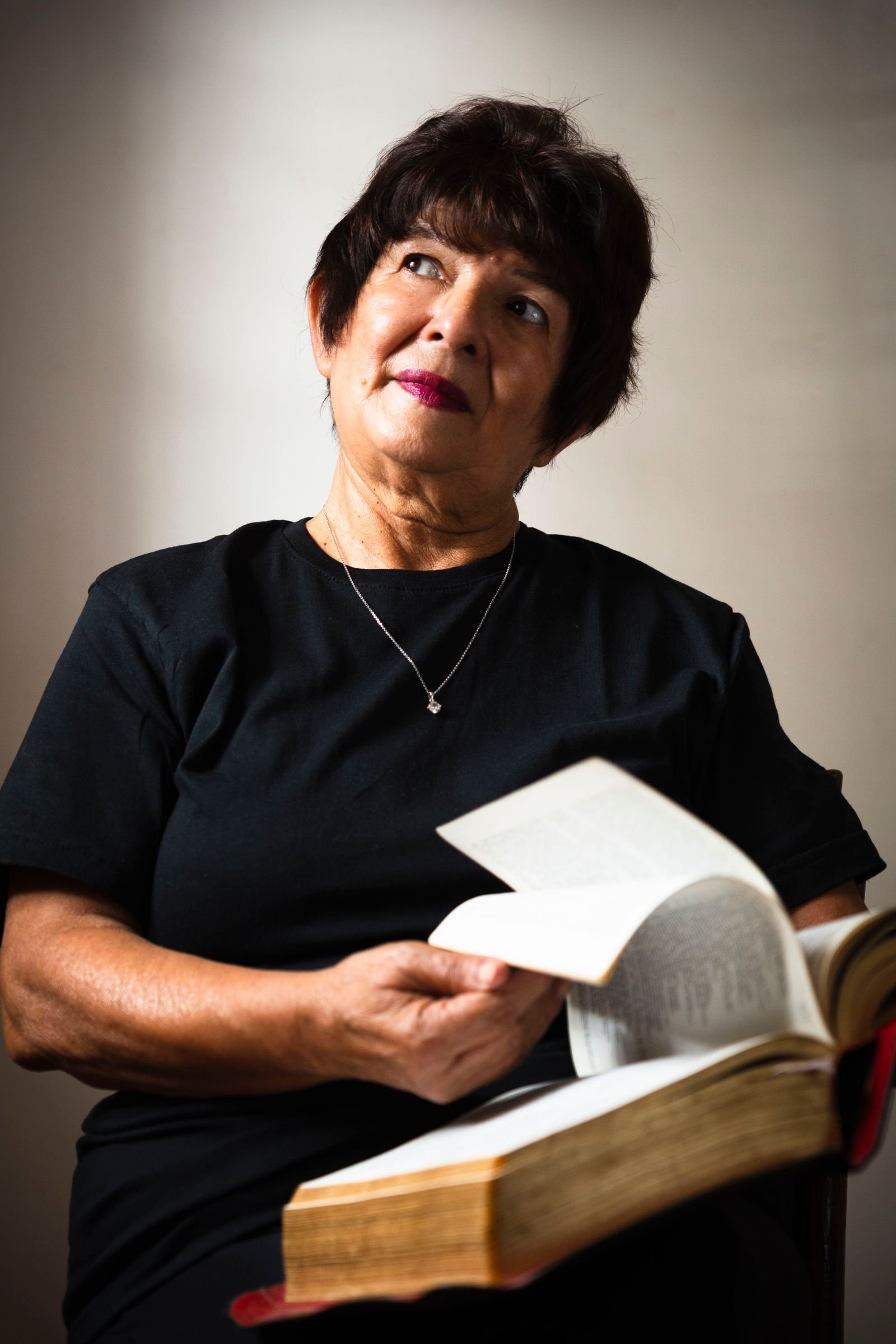 Older Hispanic woman reading a book, deep in thought