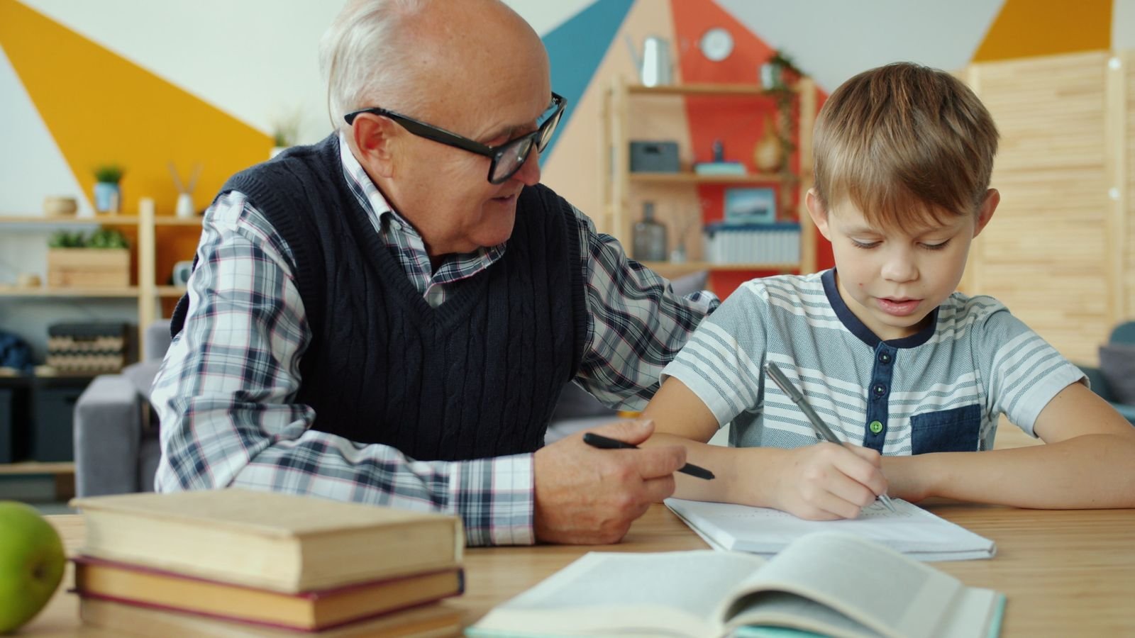 Grandfather helping his grandson with schoolwork at the kitchen table