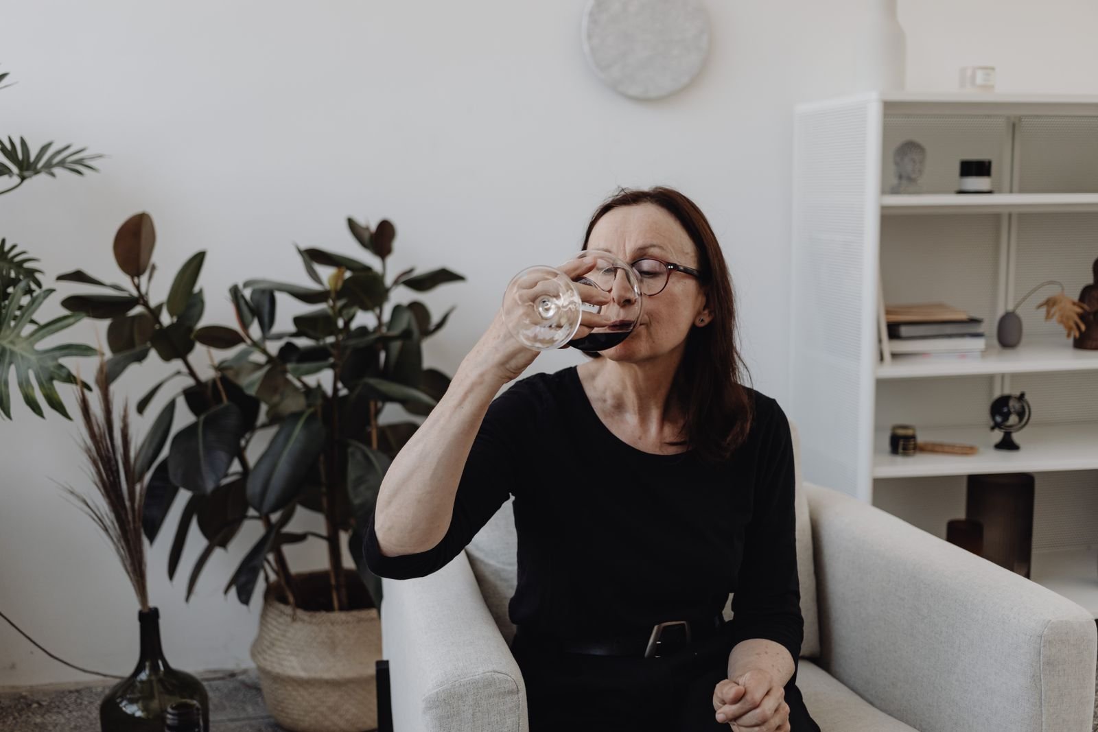Older woman sipping a glass of wine while sitting in her living room