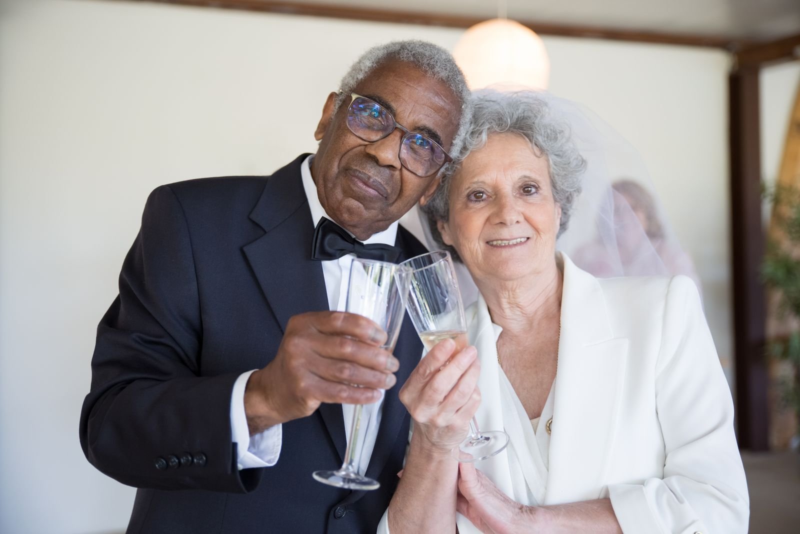 Black senior couple toasting with champagne glasses indoors