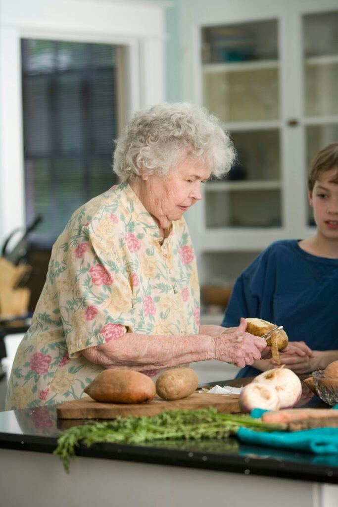 Grandmother teaching her grandson how to safely peel and prepare fresh vegetables in the kitchen