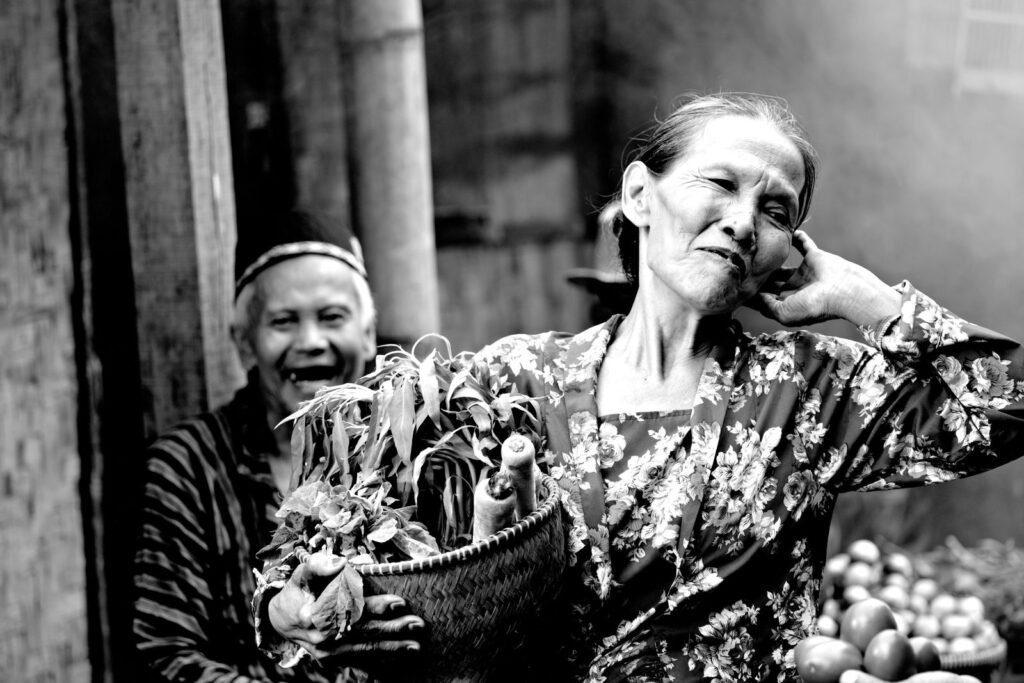Older Asian couple at an outdoor market carrying a basket of fresh produce