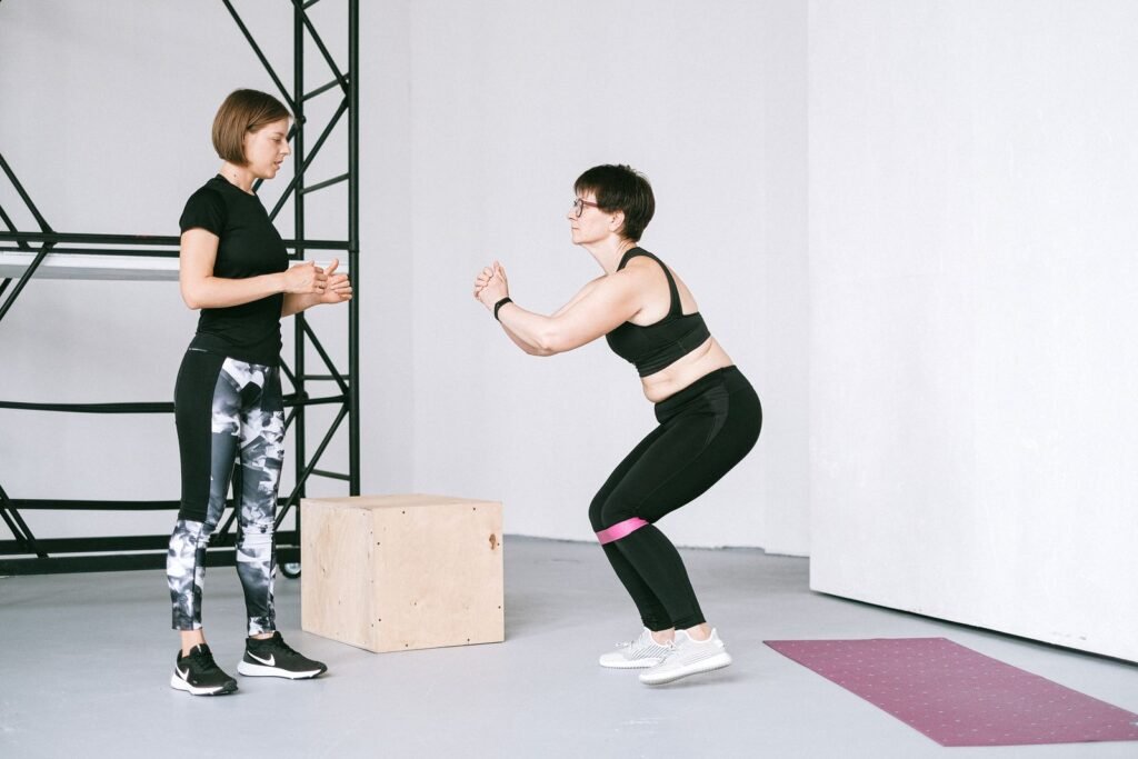 Older woman doing a resistance band exercise with a trainer guiding her
