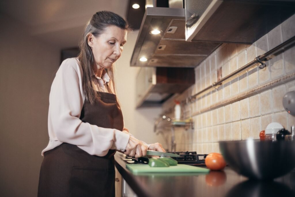 Woman in her sixties chopping fresh vegetables in her home kitchen