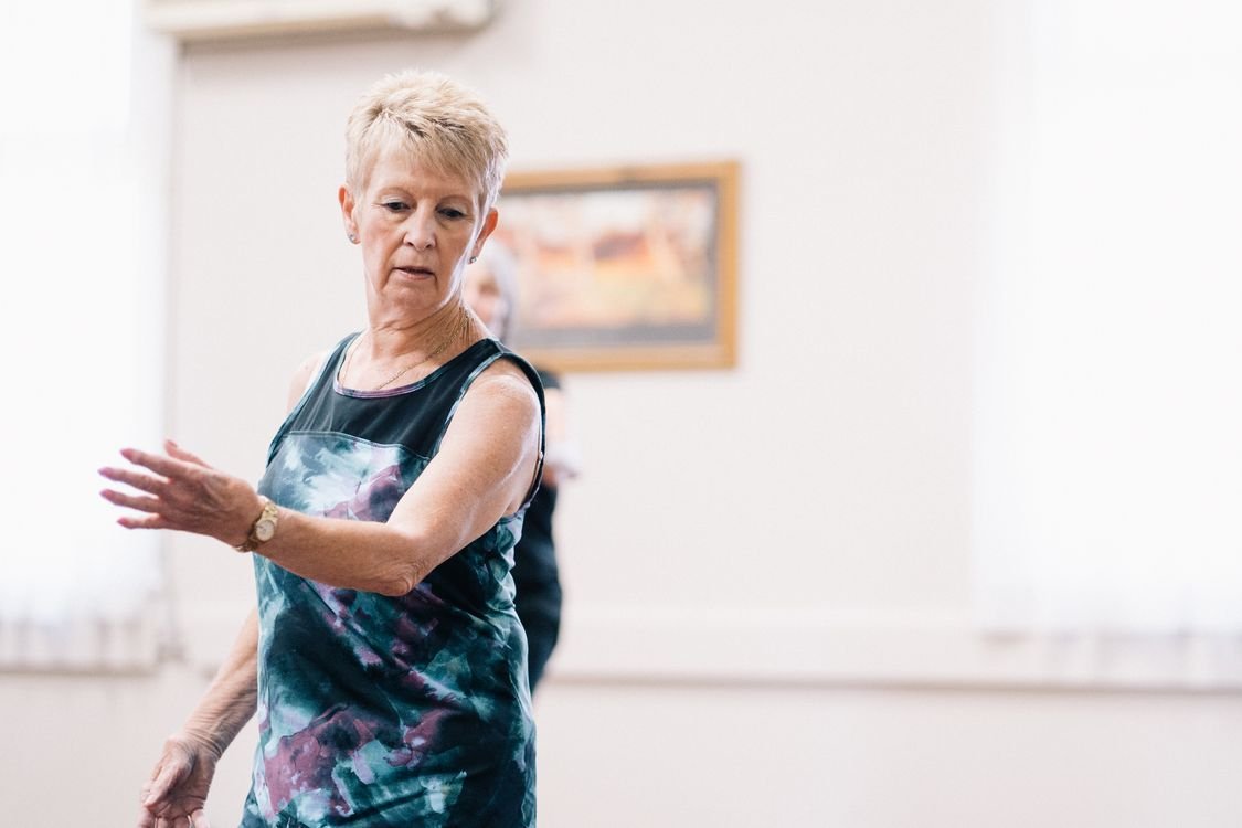 Senior woman focused and graceful during an indoor group dance exercise class
