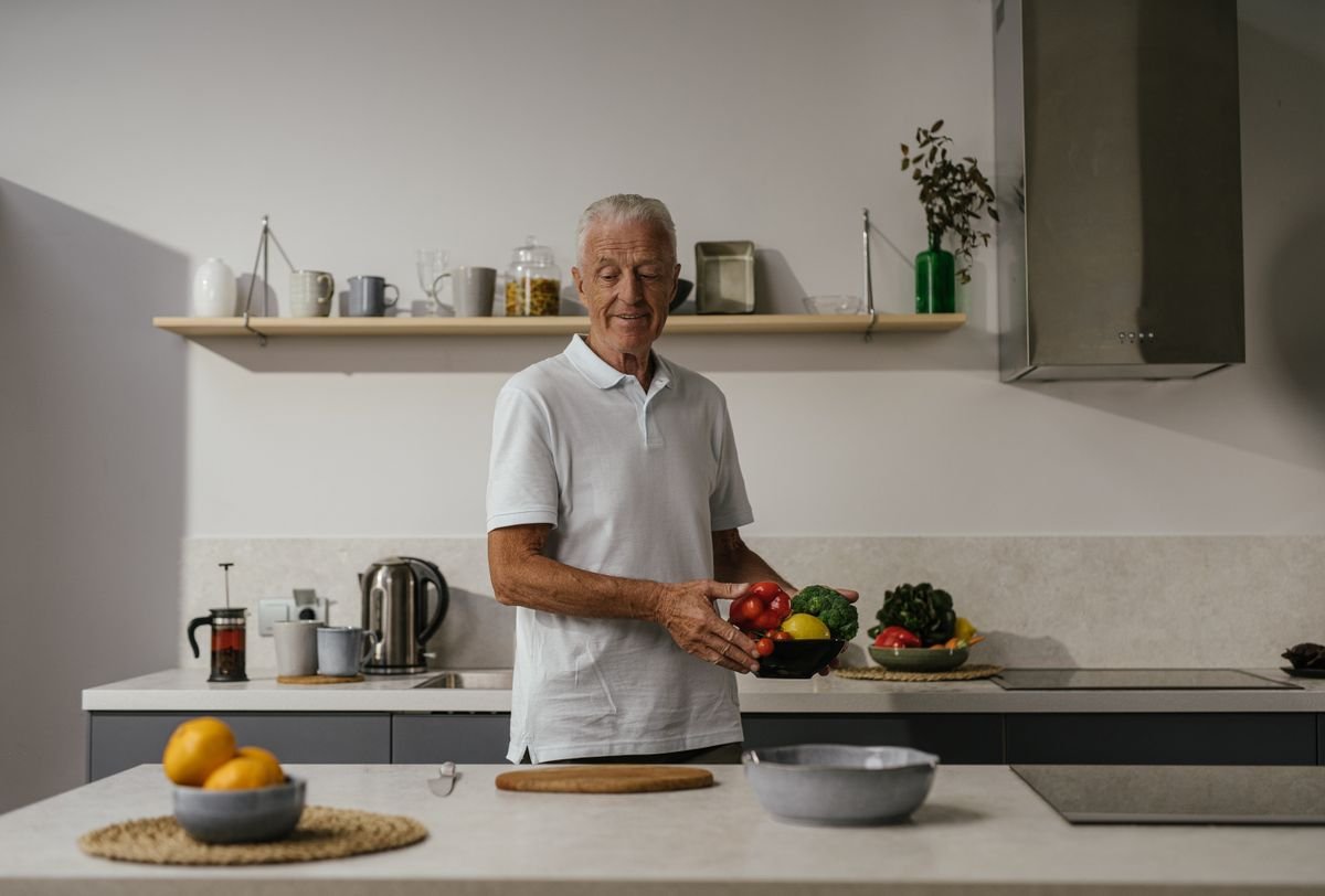 Older man preparing fresh vegetables in a bright kitchen