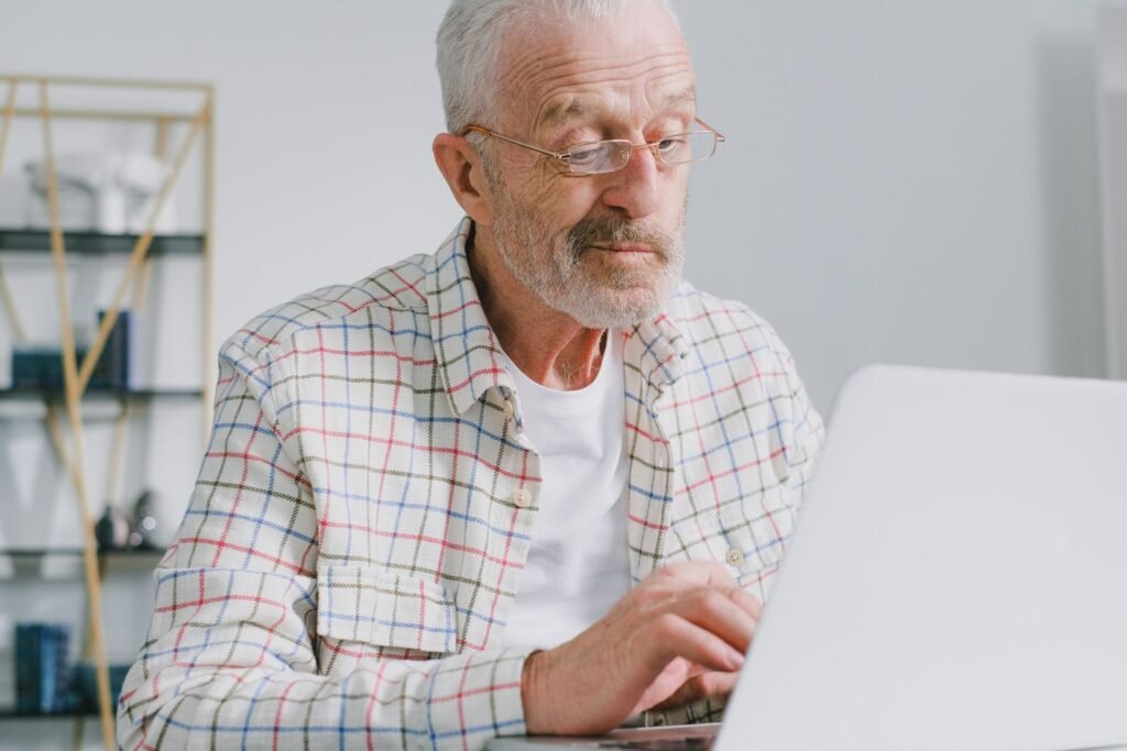 Senior man with eyeglasses working on a laptop at home