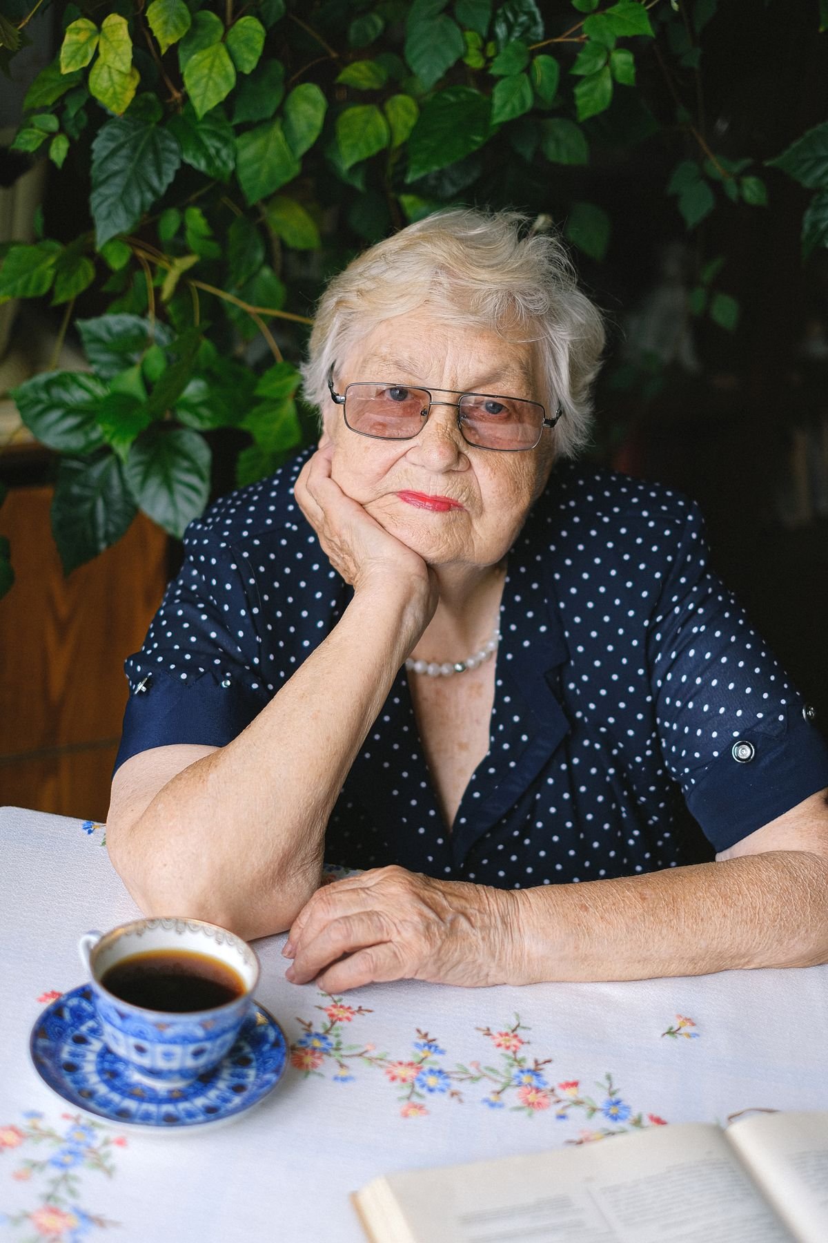 Older woman with glasses resting her chin on her hand at a table