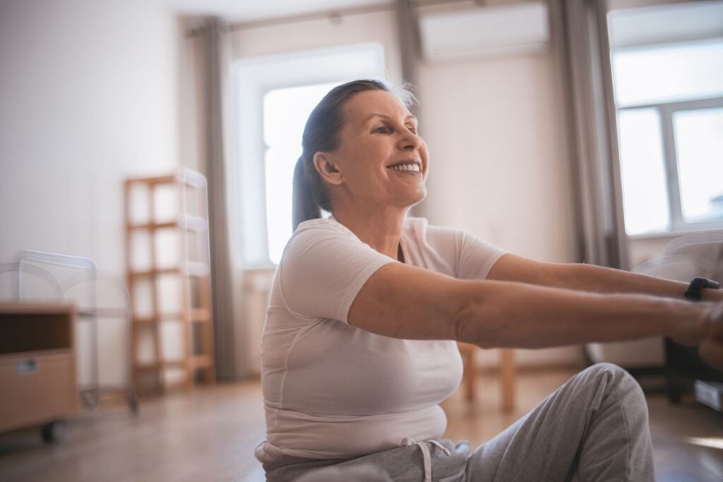 Smiling older woman doing a seated twist exercise indoors