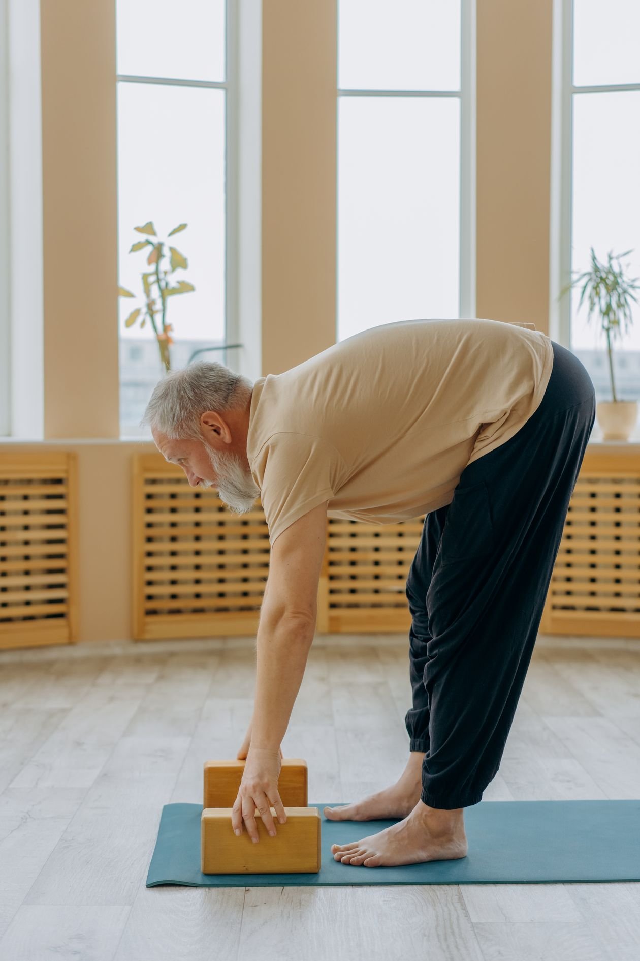 Senior man stretching on a yoga mat indoors