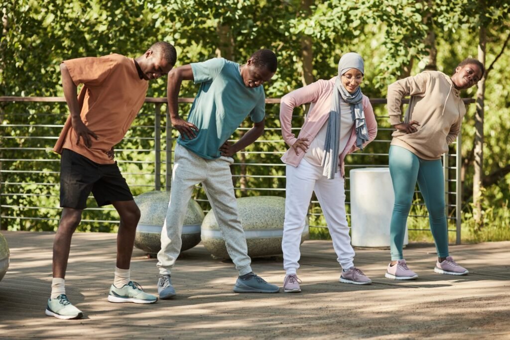 Diverse group of older adults doing a standing balance and stretching exercise together in a park